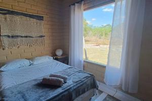 een slaapkamer met een bed en een groot raam bij Chácara Canto da Mata in Cavalcante