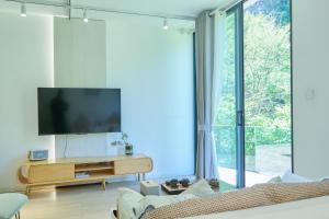 a living room with a tv and a large window at Zhumaxi Leisure Lodge in Zhangjiajie