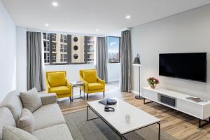 een woonkamer met een bank en 2 gele stoelen bij Meriton Suites Bondi Junction in Sydney