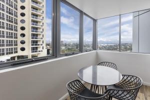 a table and chairs in a room with windows at Meriton Suites Bondi Junction in Sydney