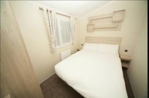 a white bed in a small room with a window at Talland view. Polperro in Looe +8 photos