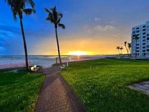 przejście na plażę z palmami i budynek w obiekcie Always Summer On a White Sandy Beach w mieście Fort Myers Beach