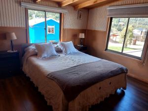 ein großes Bett in einem Zimmer mit einem großen Fenster in der Unterkunft Hostal y Cabañas Ventisquero in Puerto Puyuhuapi