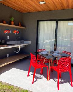 a dining room with a table and red chairs at Mani Milagres Studio - Gamboa Patacho in Pôrto de Pedras