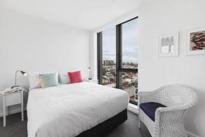 een slaapkamer met een bed, een stoel en een raam bij Smith Street Crossing - Central City-view Serenity in Melbourne