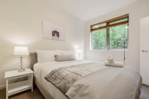 a white bedroom with a large bed and a window at Experience the St Kilda Vibe from a Cosy Retreat in Melbourne