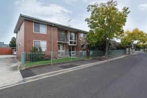 a brick building with a fence on the side of a street at Spacious Suburban Comfort Perfect for Families in Melbourne