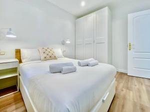 a bedroom with a large white bed with two towels on it at Puerta de Toledo VII - Apartamento de 2 dormitorios con Balcón in Madrid
