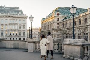 a couple standing on a bridge in front of a building at Hotel Bristol, a Luxury Collection Hotel, Vienna in Vienna