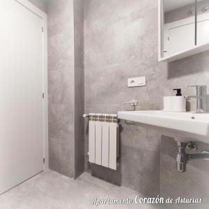 baño con lavabo blanco y armario blanco en CORAZÓN DE ASTURIAS, en Piedras Blancas