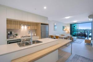 a kitchen with a sink and a living room at 'Riverfront Flow' Poolside and Portside in Hamilton in Brisbane