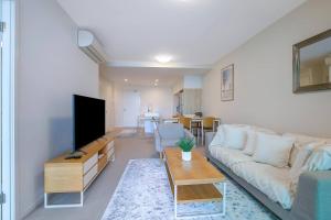 sala de estar con sofá y TV de pantalla plana en 'Riverfront Flow' Poolside and Portside in Hamilton en Brisbane