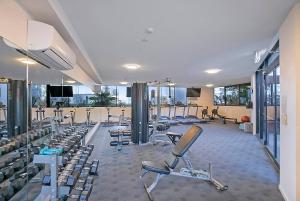 a gym with several rows of exercise bikes and treadmills at Fall in Love with Waterfront Resort-style Living in Brisbane