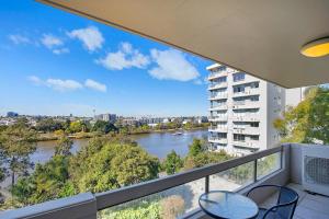 a balcony with two chairs and a view of a river at 'Riverside Terrace' Inner-city Retro-chic with Pool in Brisbane