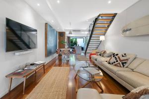 a living room with a couch and a tv at The Sun Catcher - A Trendy South Brisbane Townhouse in Brisbane