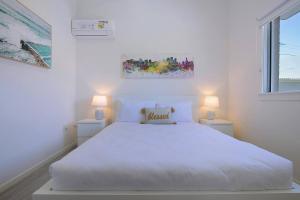 ブリスベンにあるCity Centre Comfort - Your Home in Vibrant Brisbaneの白いベッドルーム(白いベッド1台、ランプ2つ付)