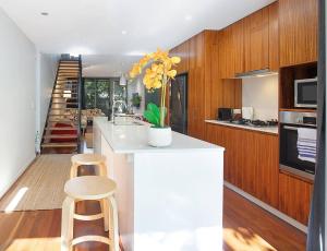a kitchen with a white counter and stools in it at The Sun Catcher - A Trendy South Brisbane Townhouse in Brisbane