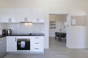 ブリスベンにあるCity Centre Comfort - Your Home in Vibrant Brisbaneの白いキャビネット付きのキッチン、ダイニングルーム