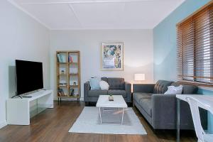 uma sala de estar com um sofá e uma televisão em 'Eucalypt Cottage' A Tranquil Family Hideaway em Brisbane