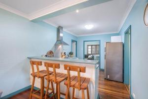 uma cozinha com paredes azuis e um bar com bancos em 'Eucalypt Cottage' A Tranquil Family Hideaway em Brisbane