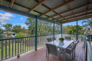 um pátio com uma mesa e cadeiras num deque em 'Eucalypt Cottage' A Tranquil Family Hideaway em Brisbane