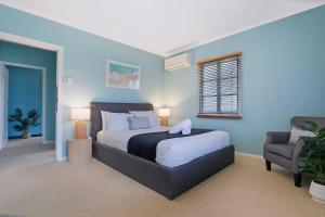 um quarto com uma cama e uma cadeira em 'Eucalypt Cottage' A Tranquil Family Hideaway em Brisbane