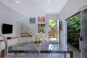 uma sala de jantar com uma mesa de vidro e cadeiras em Nundah's Lush Haven - Serene Family Townhouse Escape em Brisbane