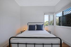 een witte slaapkamer met een bed en een raam bij Nundah's Lush Haven - Serene Family Townhouse Escape in Brisbane