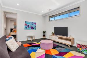 a living room with a couch and a flat screen tv at 'Brightly Brompton' A Family Delight by the Park in Bowden