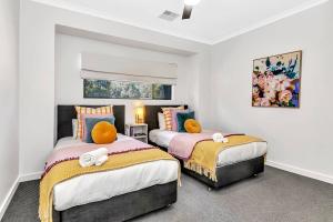 Dos camas en una habitación con paredes blancas. en 'Brightly Brompton' A Family Delight by the Park, en Adelaida