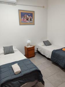 Cette chambre comprend deux lits et une table avec une lampe. dans l'établissement RESIDENCIAL SIC, à Aimogasta