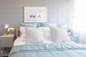 1 dormitorio con 1 cama con almohadas a rayas en Scandi Beach Breeze Minutes from Glenelg Beach en Glenelg