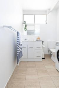 a white bathroom with a sink and a toilet at Scandi Beach Breeze Minutes from Glenelg Beach in Glenelg