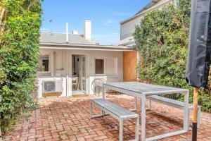 einen Tisch und eine Bank auf einer Backsteinterrasse in der Unterkunft The Lemon Tree - Charming Cottage in North Adelaide in Adelaide