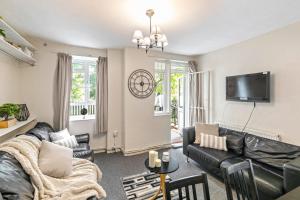 a living room with a black leather couch and a tv at 3 Bedroom Flat Near Finsbury Park, Manor House Station in London