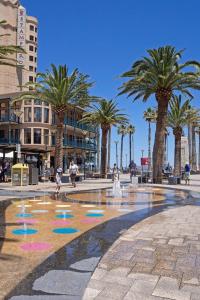 a fountain with palm trees and people walking around it at Scandi Beach Breeze Minutes from Glenelg Beach in Glenelg