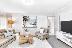 a living room with a couch and a tv at Waves and Walks - Close to Beach and Local Boutiques in Glenelg