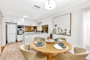 a kitchen and dining room with a wooden table and chairs at Waves and Walks - Close to Beach and Local Boutiques in Adelaide