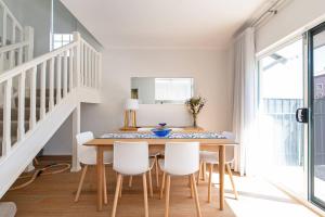 uma sala de jantar com uma mesa de madeira e cadeiras brancas em Colley's Nest - Family-friendly Townhouse with Patio em Adelaide