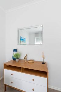 eine Holzkommode mit einem Spiegel an einer weißen Wand in der Unterkunft Colley's Nest - Family-friendly Townhouse with Patio in Adelaide + 19 Fotos
