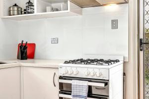 - une cuisine blanche avec cuisinière blanche four supérieur dans l'établissement East Parklands Cottage - A Dreamy Garden Hideaway, à Adélaïde 5 autres photos