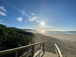 ボンビーニャスにあるCasa Mariscal perto do marの空の日が降り注ぐ浜辺のベンチ