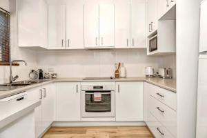 een witte keuken met witte kasten en apparaten bij 'The Redstone' Experience Adelaide's Inner-east in Kensington and Norwood