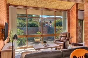 een woonkamer met een bank en een groot raam bij 'The Redstone' Experience Adelaide's Inner-east in Kensington and Norwood