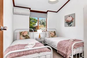 twee bedden in een kamer met een raam bij 'The Redstone' Experience Adelaide's Inner-east in Kensington and Norwood