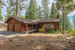 a wooden house with a porch in the woods at Cozy Home with Lake Views Decks Hot-Tub Walk to Private HOA Beach in 5 min in Tahoe City