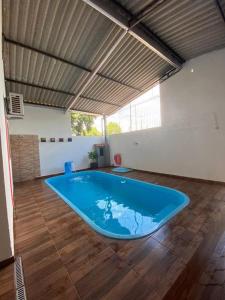 een groot blauw zwembad in een kamer met een houten vloer bij Rancho Imperador in Pôrto Primavera