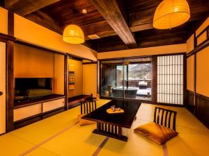 a living room with a dining table and a television at Yukai Resort Terunoyu in Maniwa