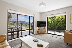 a living room with a tv and large windows at The View 2 bed unit with stunning Hobart outlook in Hobart