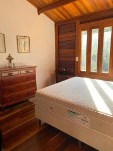 a bedroom with a bed and a dresser at Casa Floresta do Uaimii in Ouro Preto +5 photos